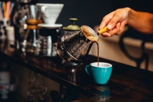 Barista pouring coffee into a blue cup