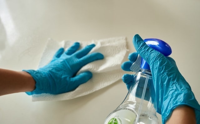 Close up of person wearing gloves and cleaning a counter