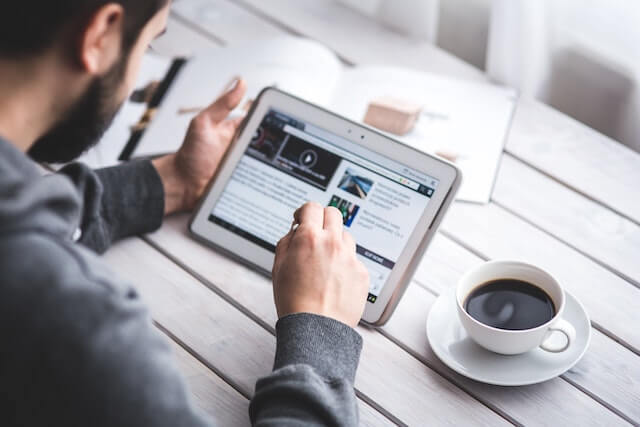 Man drinking coffee and reading his tablet