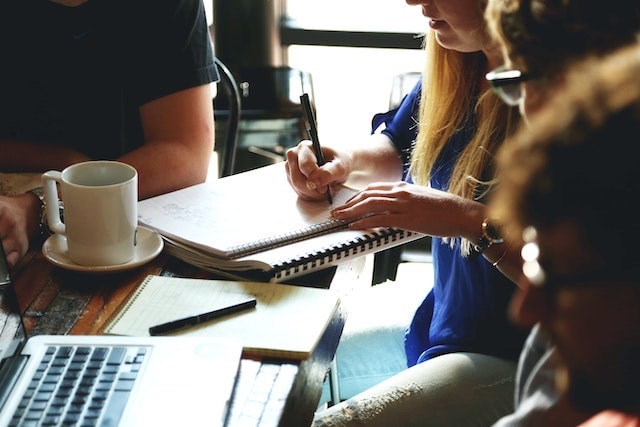 People in a meeting with one person taking notes