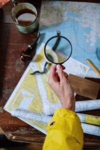 Person holding a magnifying glass to a world map.