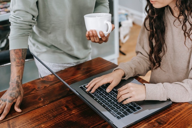 Person standing next to someone using a laptop