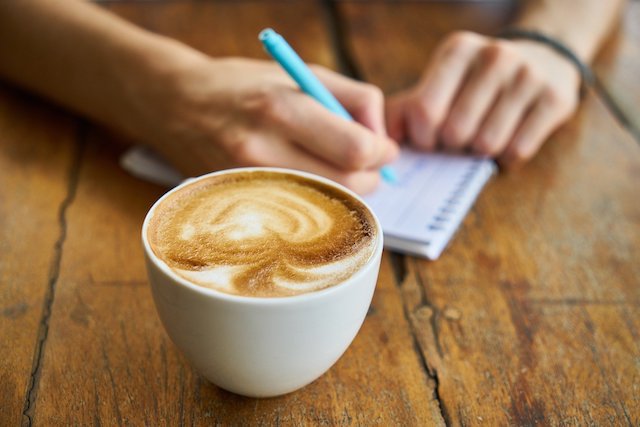 Person with a cup of coffee and a notepad