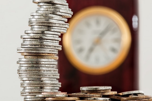 Side Hustle Stack of Coins with Clock in Background