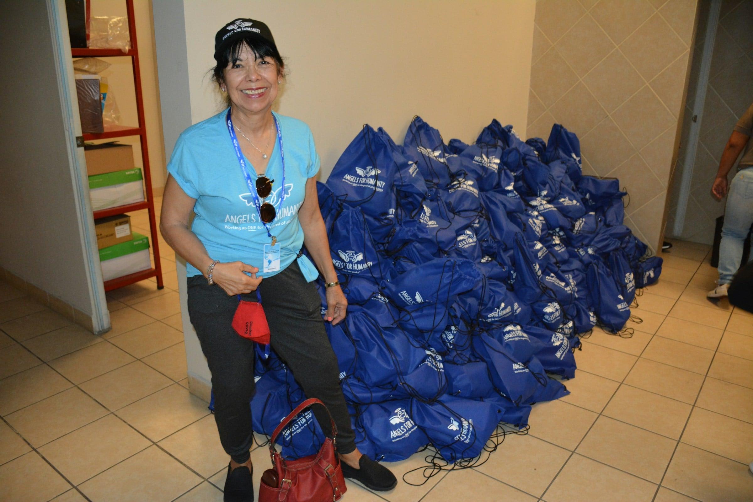 Smiling woman standing near a pile of blue bags