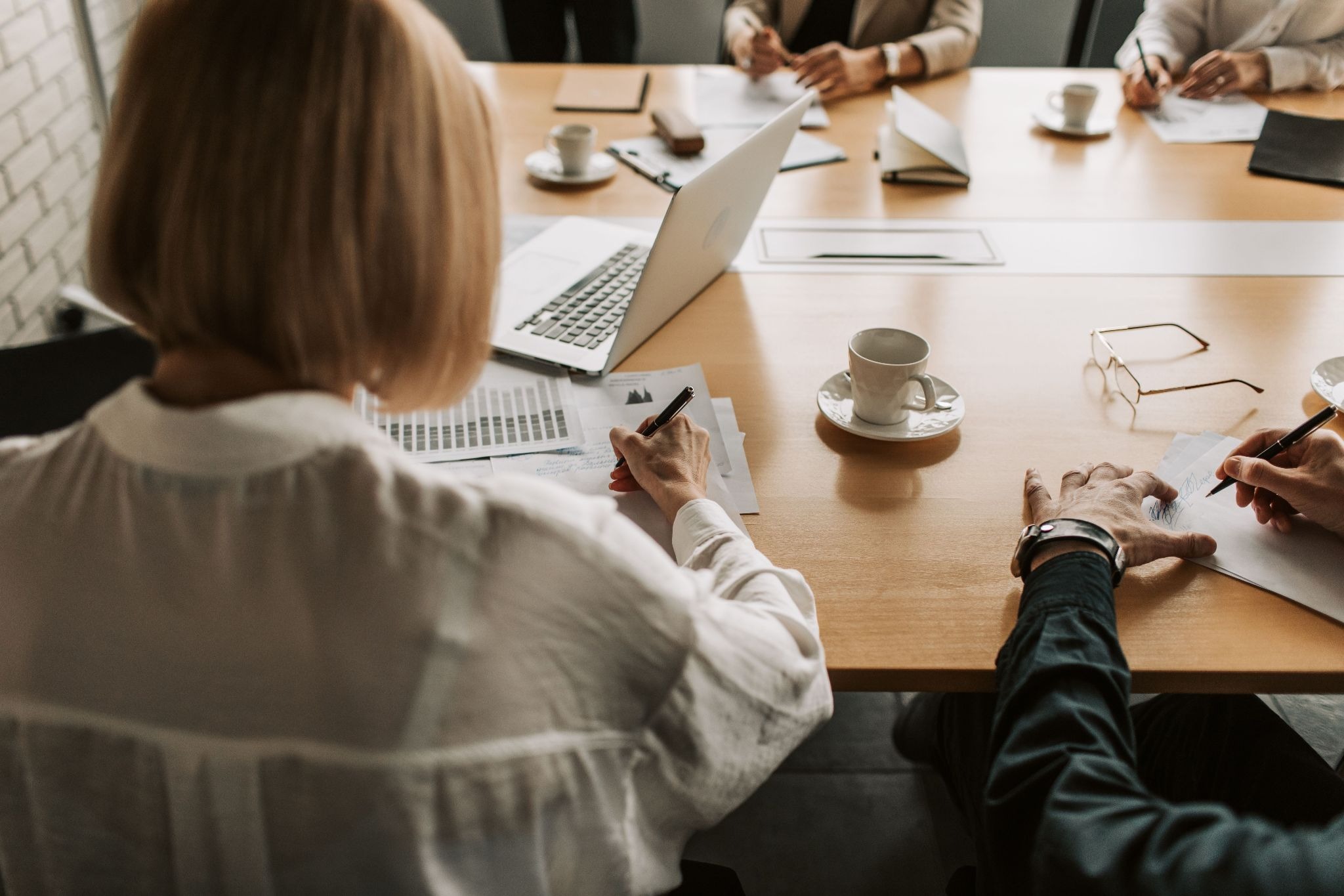 People sitting at a meeting around a conference table with documents and laptops