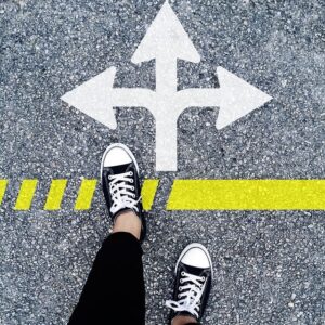 View of person's feet on pavement near direction sign