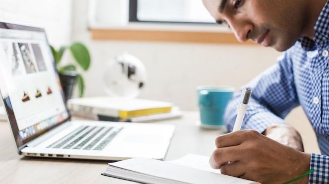 Man Working at Desk with Pen and Paper