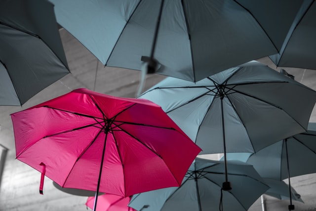 Red umbrella among gray umbrellas