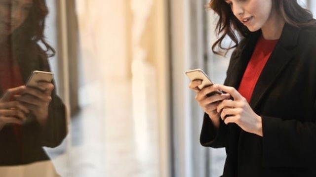 Woman standing near a shop window looking at her smartphone