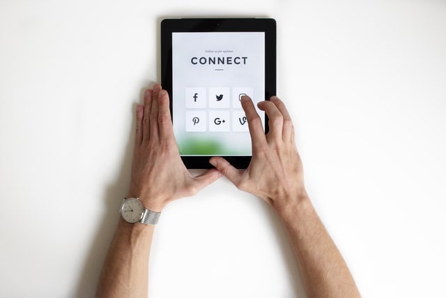 Man Holding a Tablet with Six Social Media Tools Displayed