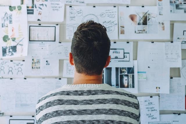 Man looking at wall with papers tacked to it