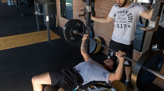 Man standing over a weightlifter