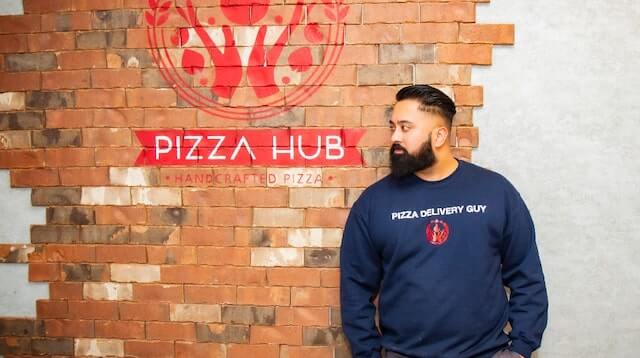 Harpreet Munjal standing beside the pizza hub sign