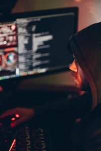 Man in black hoodie looking at computer screens