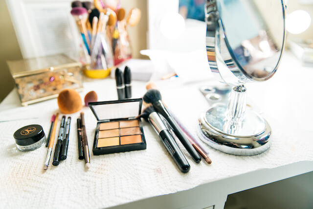 Cosmetic brushes and eye palette spread out on table