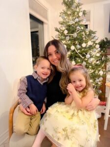 Stephanie sitting with her two children in front Christmas tree