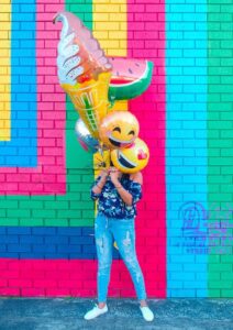 Woman with emoji balloons covering her face