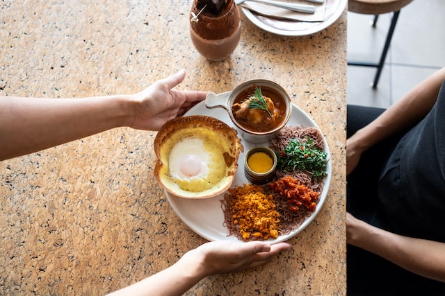 Close-up of someone serving a plate of food to a customer