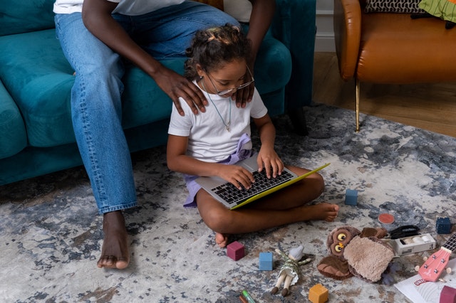Father looking over daughter’s shoulder at screen