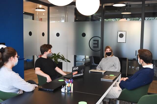 Four people wearing masks sitting together