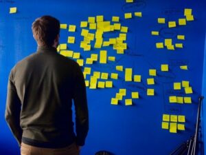 Man facing a wall with numerous sticky notes