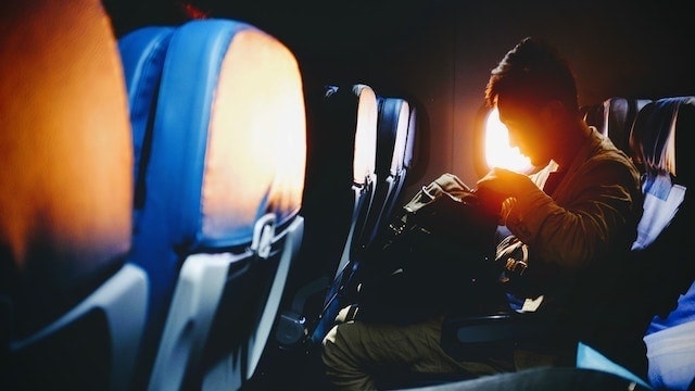 Man seated on airplane with a backpack