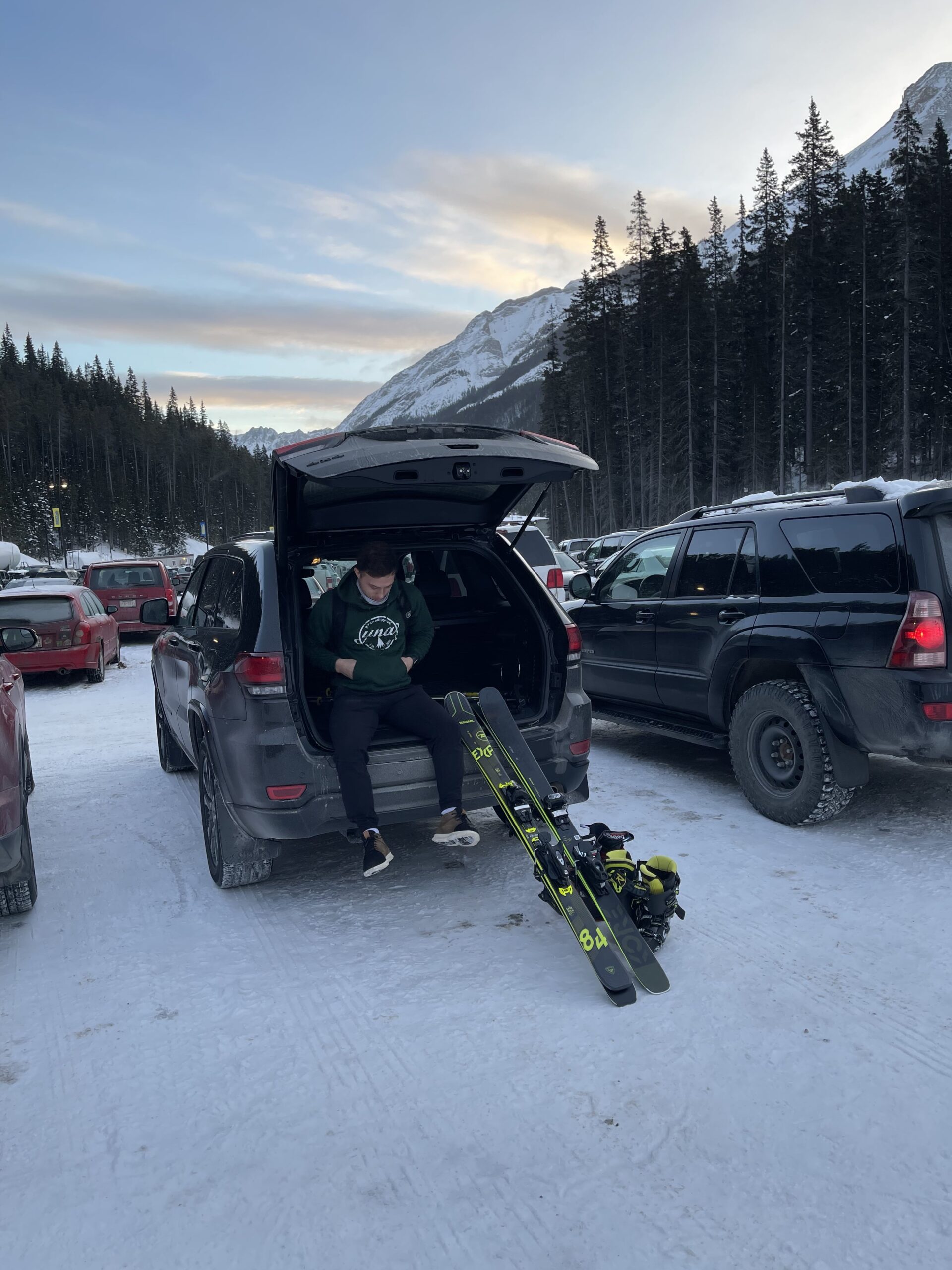 Man sitting in the back of an SUV with skis