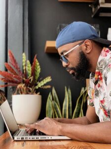 Man with blue hat working on a laptop