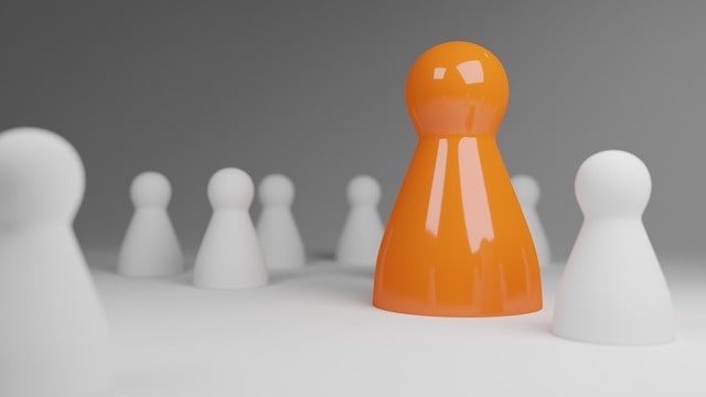 Orange board game token rising above white tokens