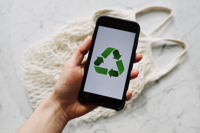 Person holding cell phone showing the recycling logo