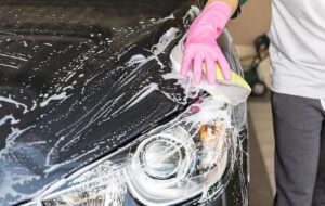 Person washing a car with a yellow sponge