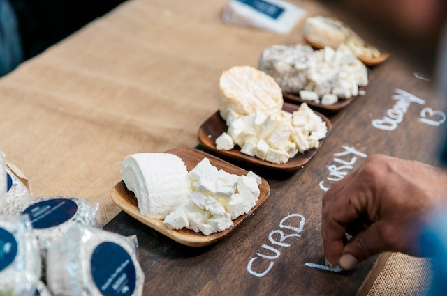 Person writing the names of cheese samples on a board