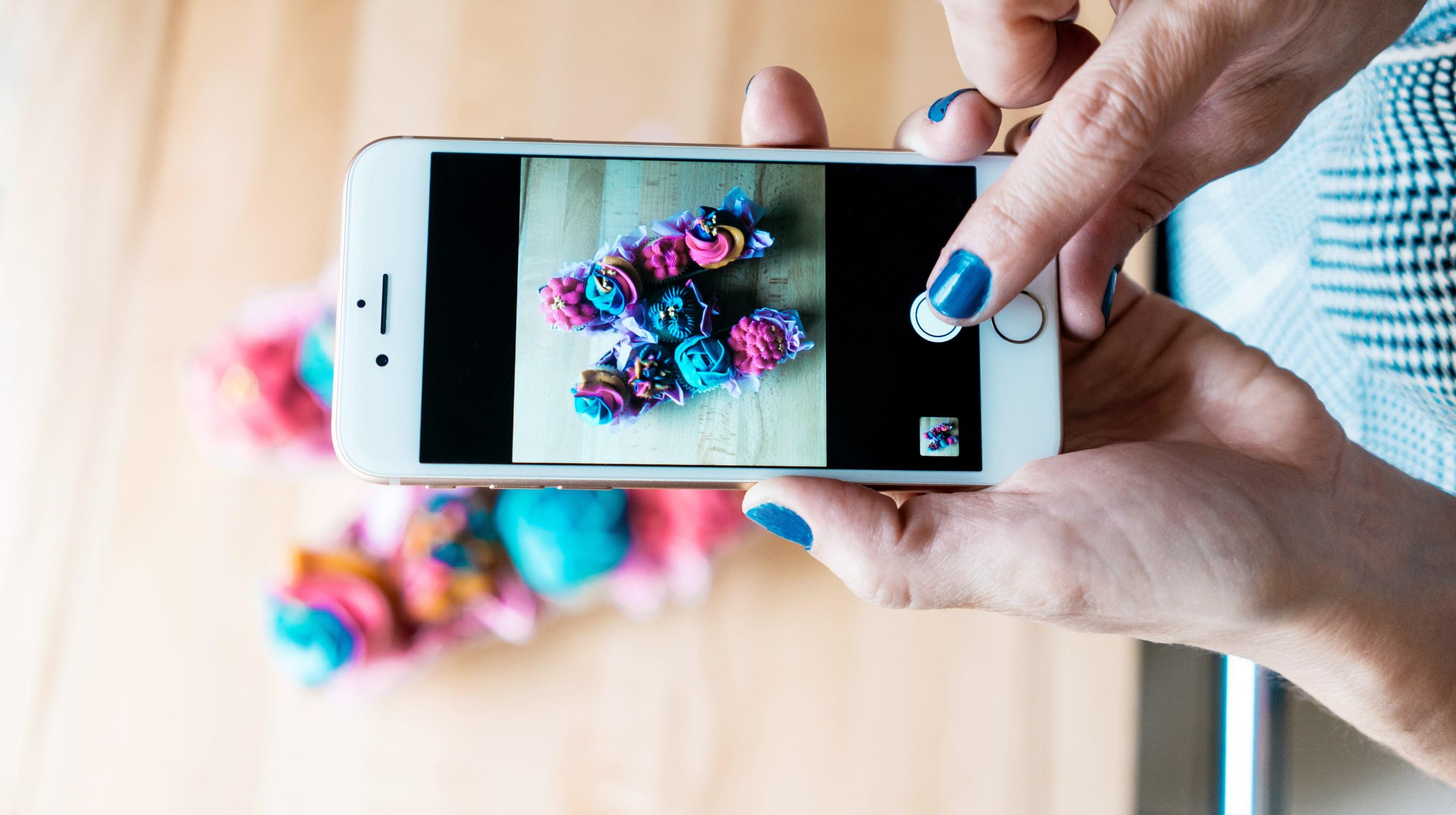 Person photographing cupcakes on their phone