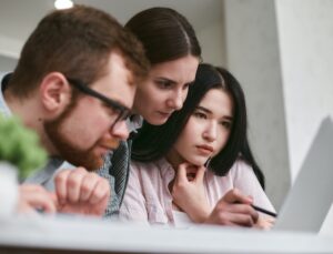 Three people looking intently at something on a computer