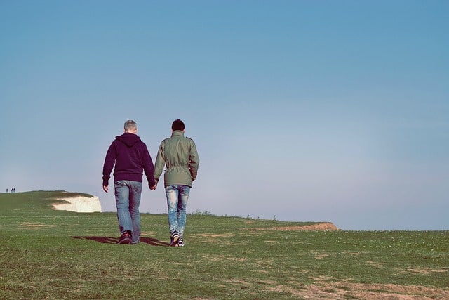 Two men holding hands as they walk outdoors.