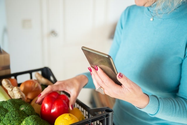 Woman holding mobile phone and going through her grocery delivery