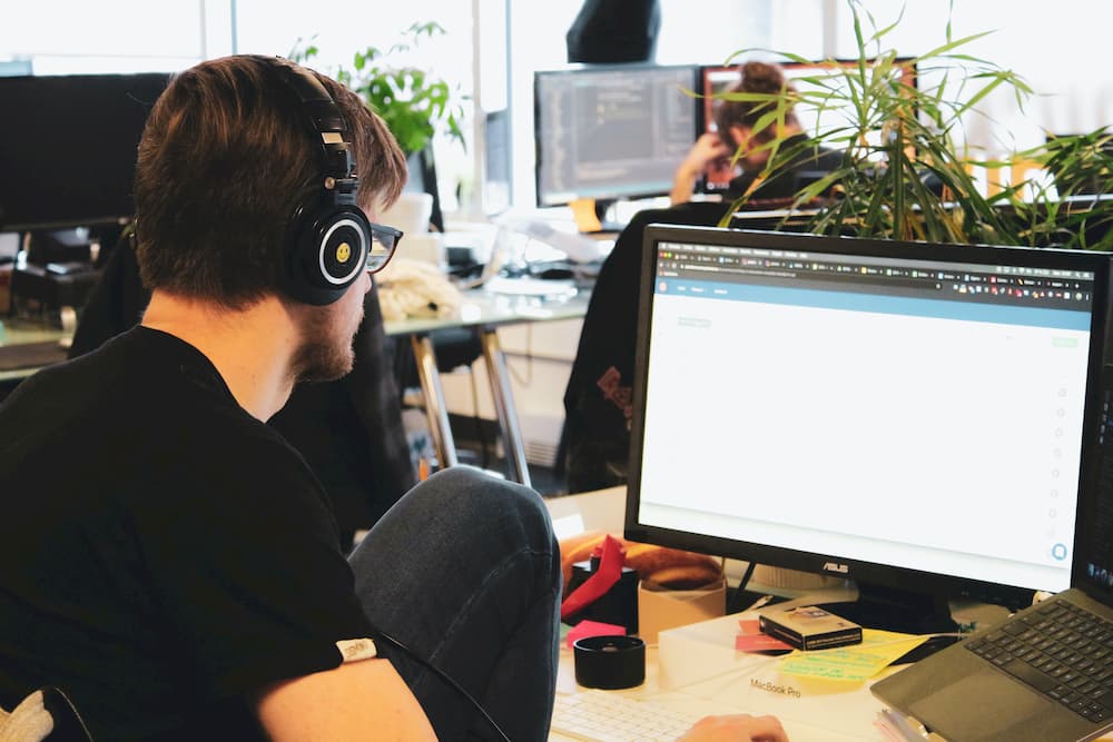 Imagen de un chjco trabajando con el ordenador de empresa, usando unos auriculares para concentrarse.