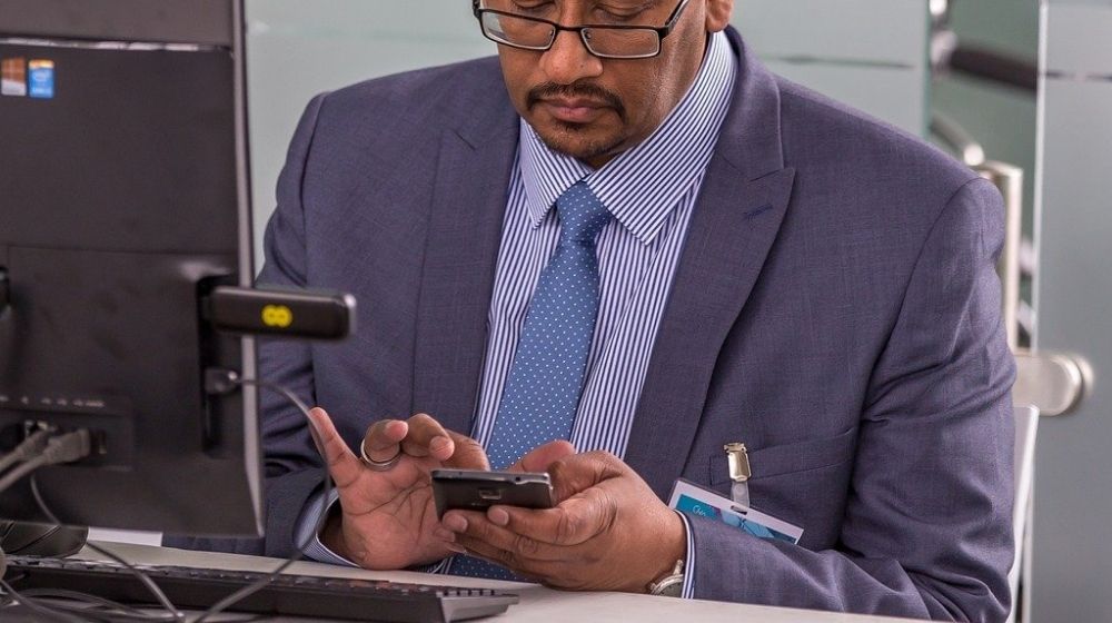 IT consultant sitting at his desk with a smartphone