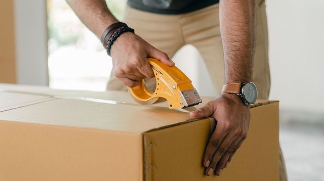 Man Taping a Cardboard Box Closed