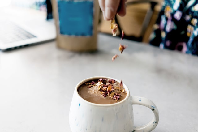 Person Adding Dried Flowers to Cup of Tea