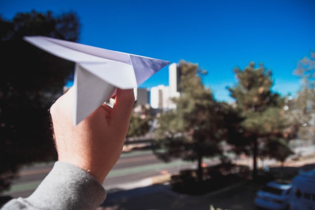 closeup of a hand holding a paper airplane