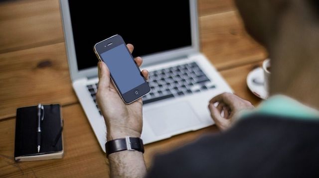 Upskill Man Sitting at Laptop with Smartphone