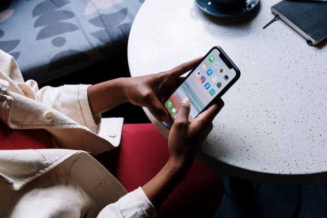 Woman Sitting at Cafe Table Looking at Phone