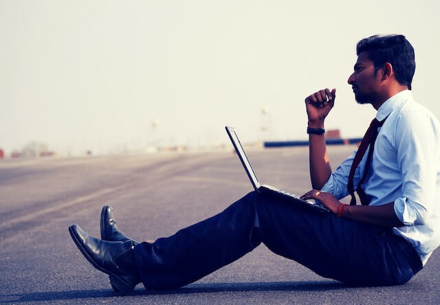 Businessman sitting on blacktop with laptop