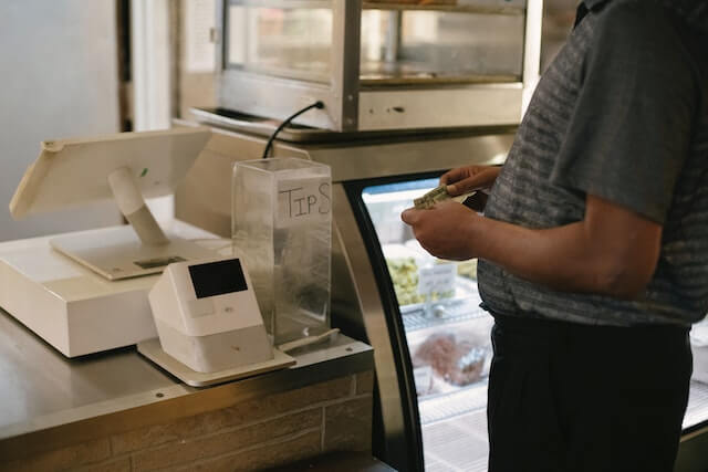 Customer standing near register with cash in hand