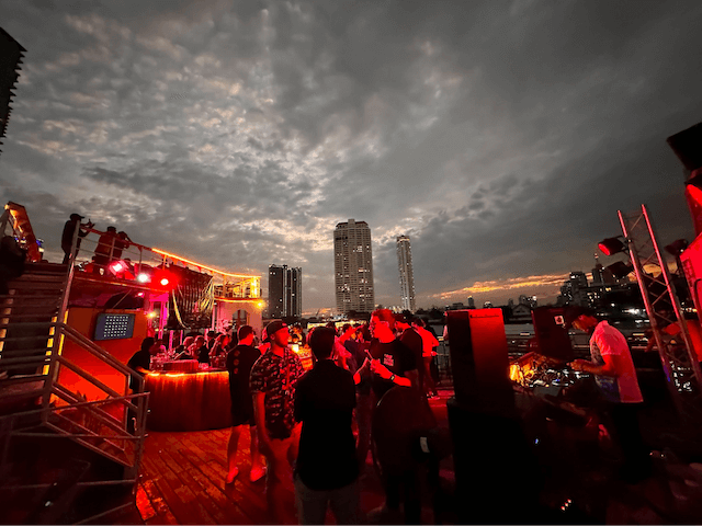 People chatting near the DJ at the GoDaddy boat party