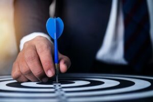 Man in business suit placing dart on a bull's eye