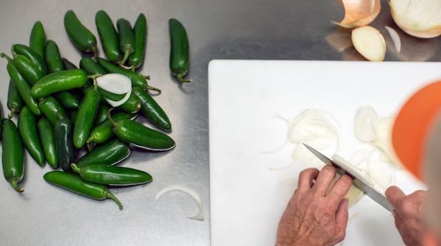 Person chopping vegetables in a commercial kitchen