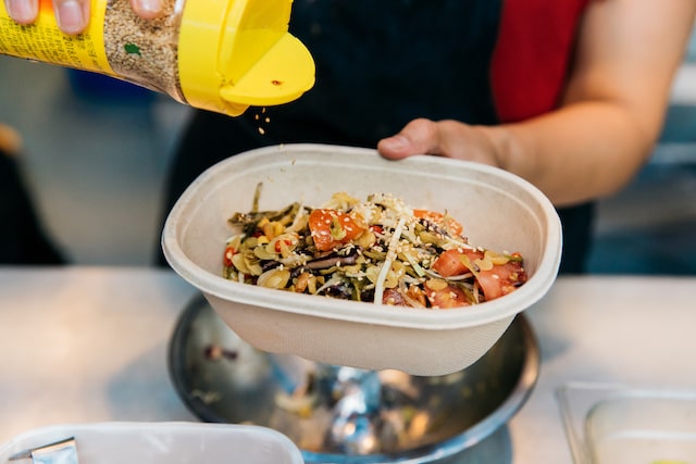 Person seasoning food in a disposable bowl